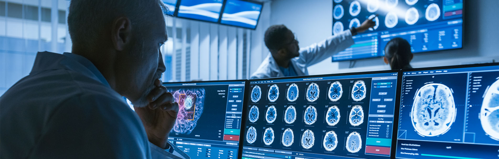 Over the Shoulder Shot of Senior Medical Scientist Working with CT Brain Scan Images on a Personal Computer in Laboratory. Neurologists in Research Center Work on Brain Tumor Cure.